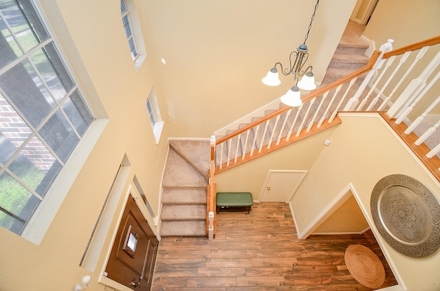 stairway featuring a chandelier, wood finished floors, and a towering ceiling