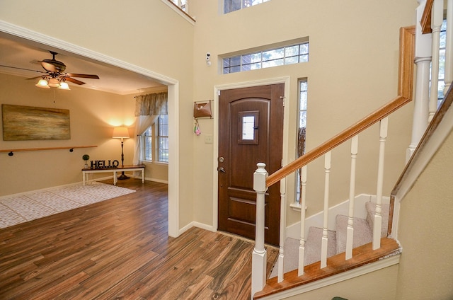 entrance foyer featuring stairway, a high ceiling, dark wood-type flooring, a ceiling fan, and baseboards