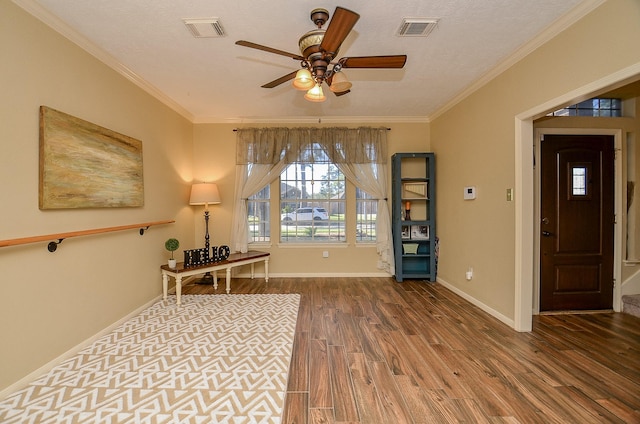 office space with ornamental molding, visible vents, baseboards, and wood finished floors