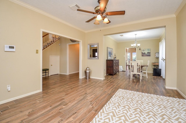 living room featuring baseboards, visible vents, stairway, wood finished floors, and crown molding