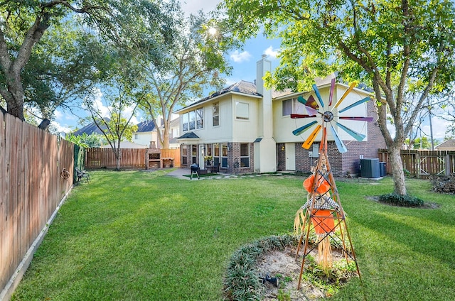 rear view of property featuring a yard, a fenced backyard, central AC unit, and brick siding