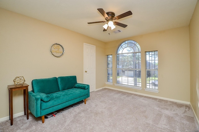 sitting room with a ceiling fan, light colored carpet, visible vents, and baseboards