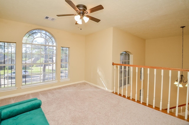 unfurnished room with carpet, visible vents, a ceiling fan, a textured ceiling, and baseboards