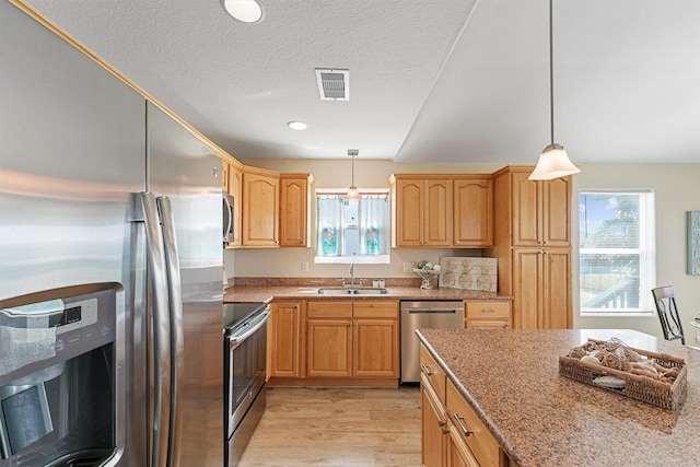 kitchen featuring a sink, visible vents, appliances with stainless steel finishes, light wood-type flooring, and light stone countertops