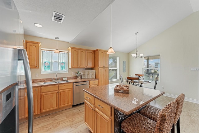 kitchen featuring visible vents, a kitchen breakfast bar, a center island, stainless steel appliances, and a sink