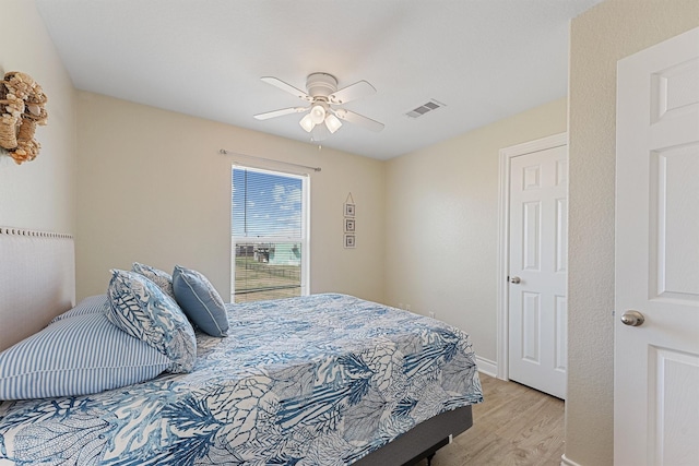 bedroom featuring light wood-style floors, baseboards, visible vents, and a ceiling fan