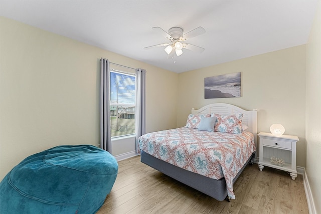 bedroom with ceiling fan, wood finished floors, and baseboards