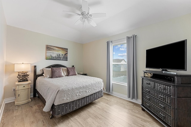 bedroom featuring vaulted ceiling, baseboards, a ceiling fan, and light wood-style floors