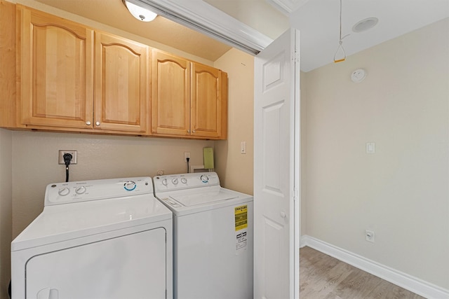 clothes washing area featuring light wood-style flooring, independent washer and dryer, cabinet space, and baseboards