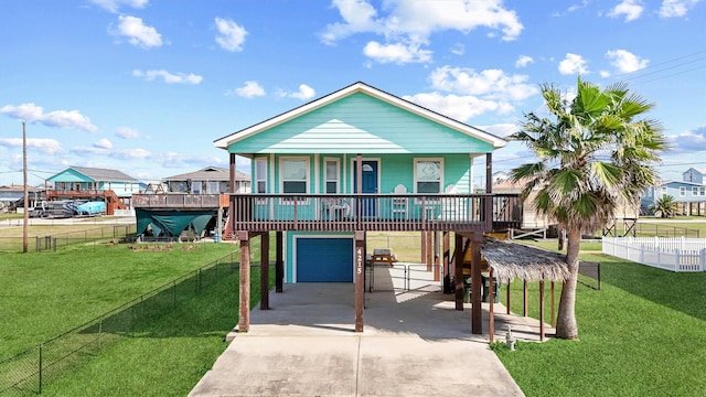 coastal home with concrete driveway, fence, a front lawn, and an attached garage