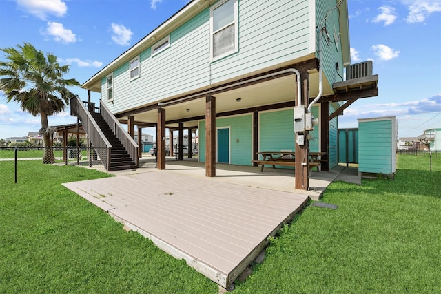 back of house featuring stairs, fence, a deck, and a lawn