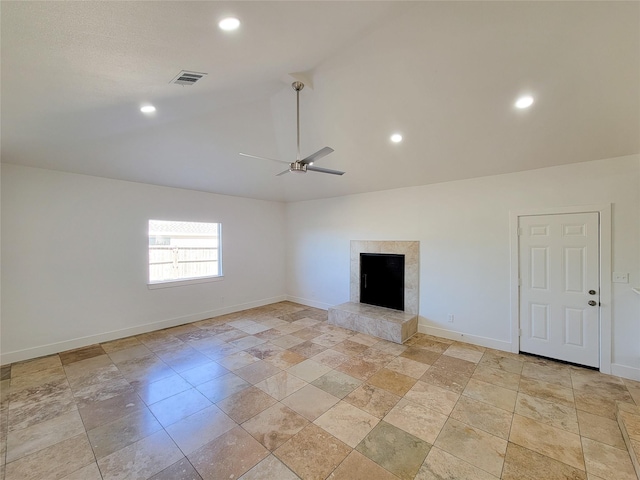 unfurnished living room with lofted ceiling, ceiling fan, a fireplace, visible vents, and baseboards