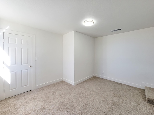 carpeted spare room featuring baseboards and visible vents