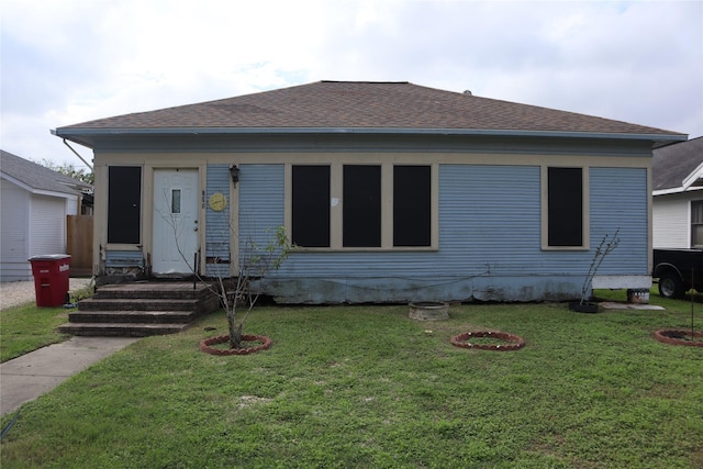 view of front facade with a shingled roof, a front yard, and entry steps