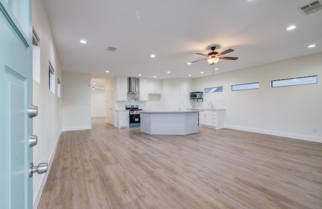 kitchen with visible vents, open floor plan, appliances with stainless steel finishes, wall chimney exhaust hood, and white cabinets