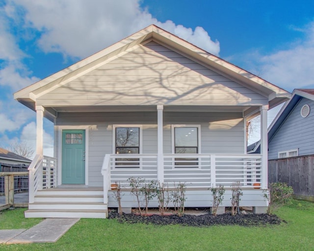 view of front of house with a porch, fence, and a front yard