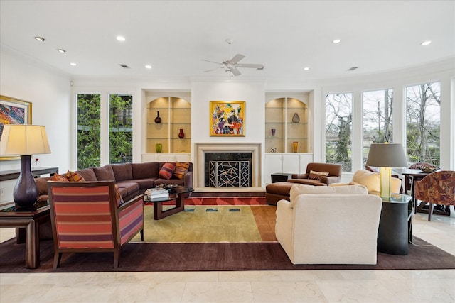 living room featuring built in features, a fireplace with raised hearth, crown molding, and recessed lighting