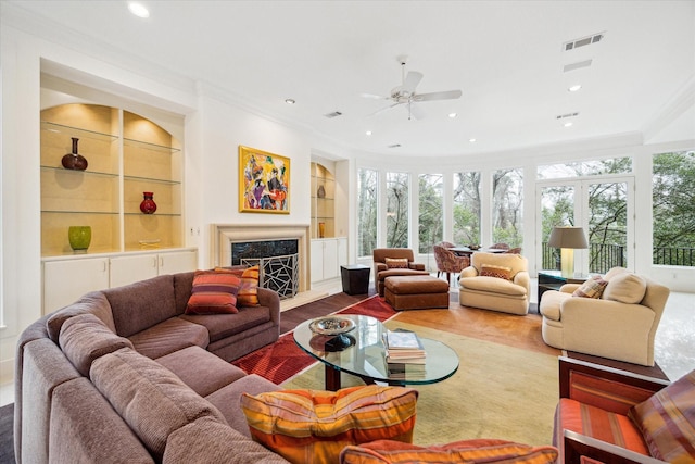 living room featuring visible vents, built in features, a premium fireplace, wood finished floors, and recessed lighting