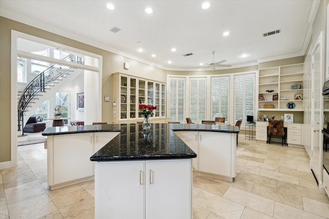 kitchen with crown molding, white cabinetry, visible vents, and a center island