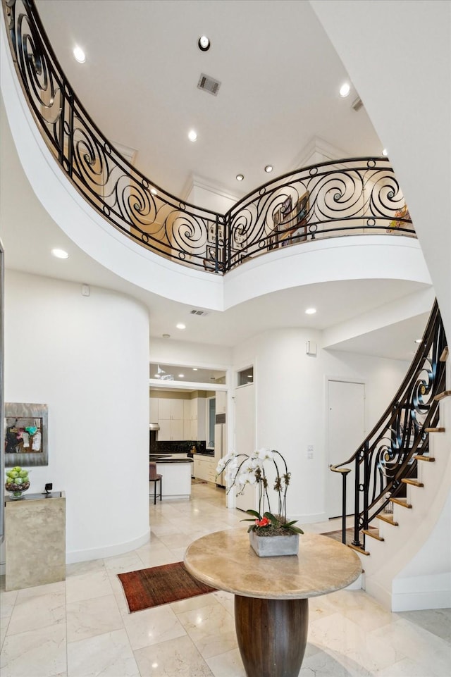 entrance foyer featuring marble finish floor, visible vents, baseboards, and a high ceiling