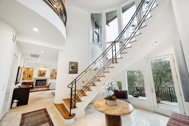 entryway with stairway, recessed lighting, a fireplace, and a towering ceiling