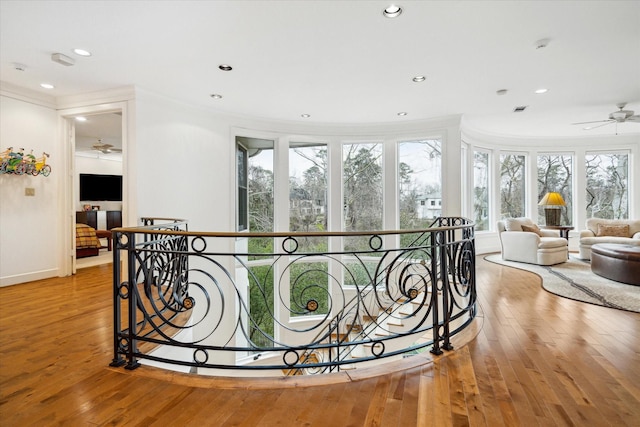 corridor with recessed lighting, wood-type flooring, crown molding, and an upstairs landing