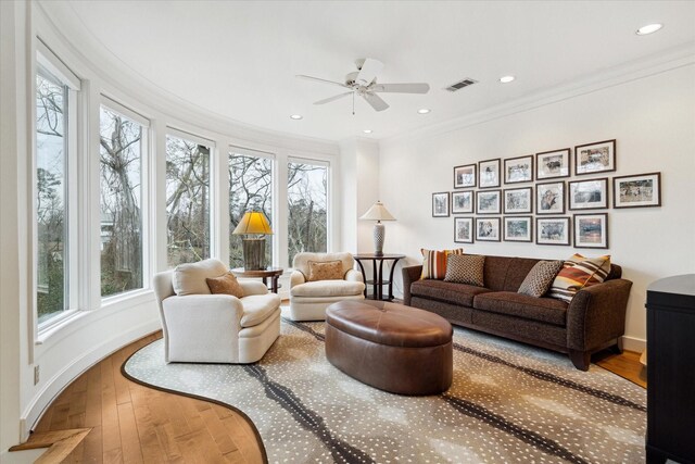 living area featuring recessed lighting, visible vents, baseboards, wood-type flooring, and crown molding