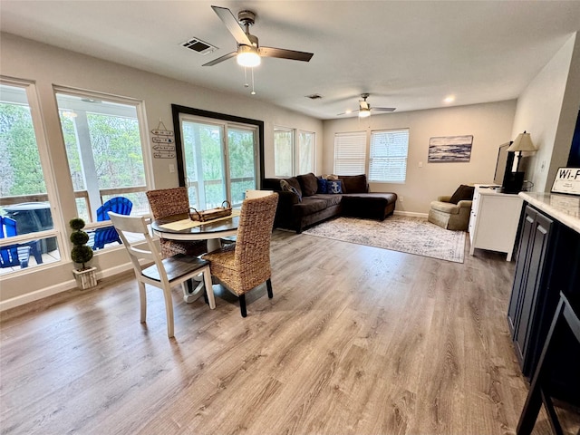 dining room featuring baseboards, ceiling fan, visible vents, and light wood-style floors