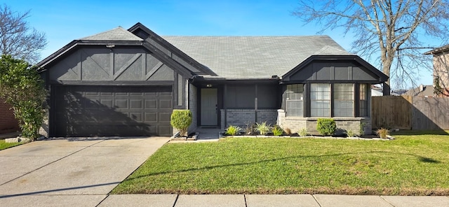 english style home featuring an attached garage, driveway, a front yard, and fence