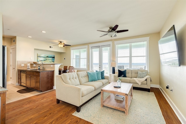 living room featuring ceiling fan, light wood-style flooring, and baseboards