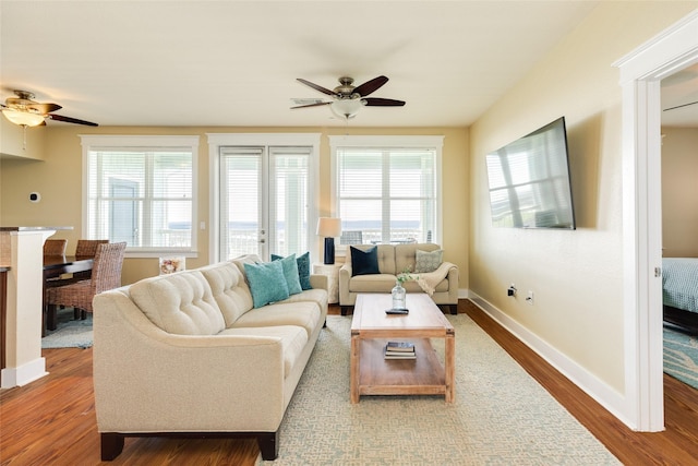 living area with dark wood-type flooring, plenty of natural light, baseboards, and a ceiling fan