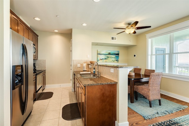 kitchen featuring brown cabinets, a breakfast bar area, stainless steel appliances, a sink, and a peninsula