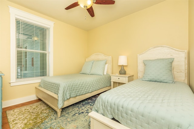 bedroom with wood finished floors, a ceiling fan, and baseboards