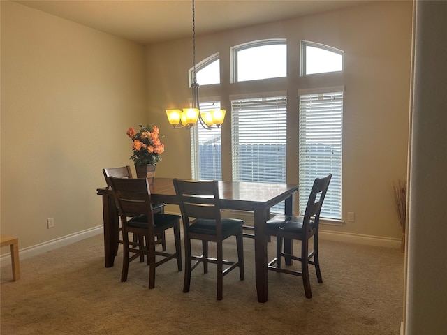 carpeted dining room with baseboards and an inviting chandelier