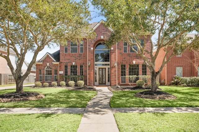 traditional-style home featuring a front yard and brick siding