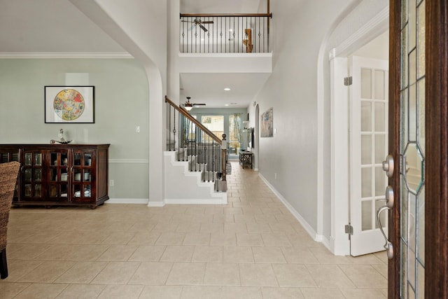 tiled foyer with baseboards, arched walkways, ceiling fan, stairs, and french doors