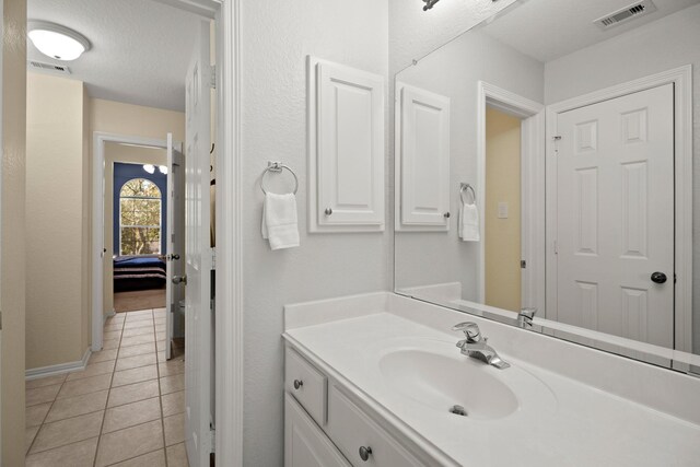 bathroom with vanity, visible vents, a textured ceiling, and tile patterned floors