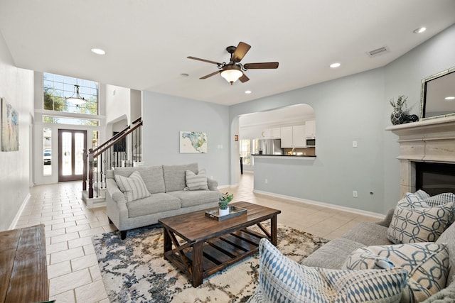 living area with light tile patterned flooring, recessed lighting, visible vents, stairway, and a glass covered fireplace