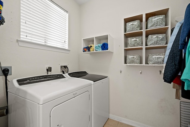 washroom with laundry area, baseboards, washing machine and clothes dryer, and light tile patterned floors