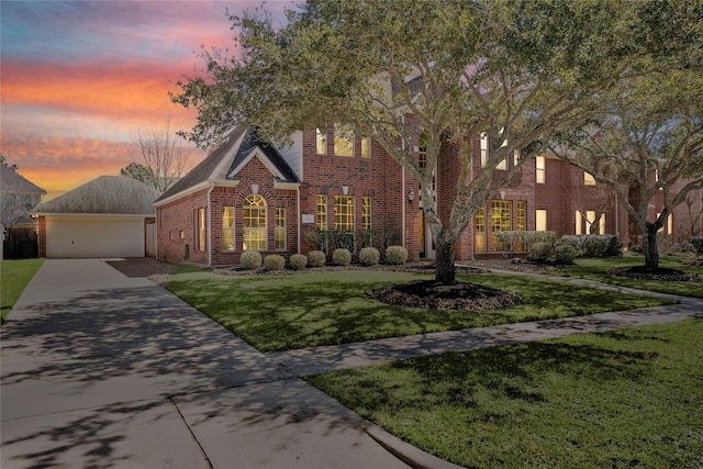 view of front of home featuring a garage, brick siding, an outdoor structure, and a front lawn