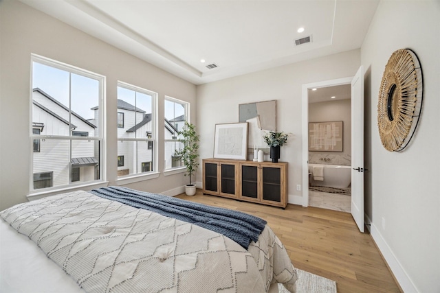 bedroom with wood finished floors, visible vents, and baseboards