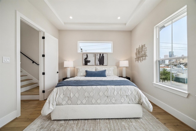 bedroom featuring baseboards, wood finished floors, multiple windows, and recessed lighting