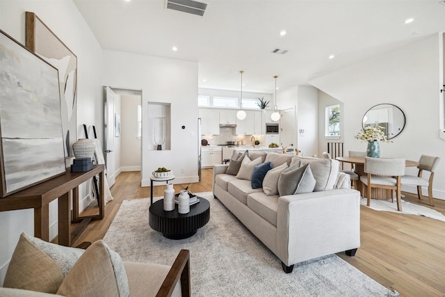 living room featuring light wood finished floors, baseboards, visible vents, and recessed lighting