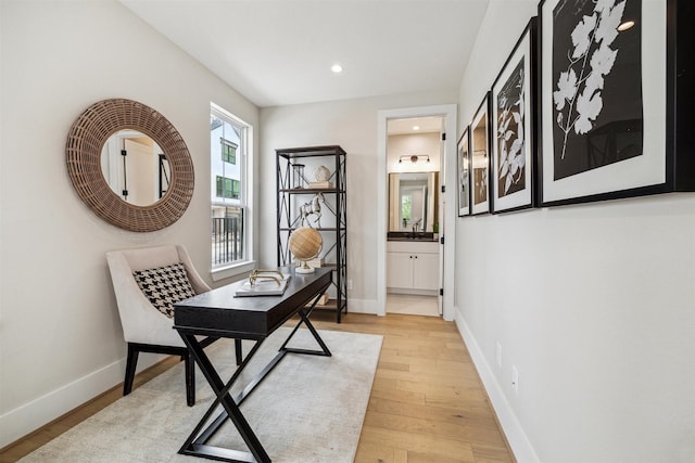 home office featuring recessed lighting, light wood-type flooring, baseboards, and a sink