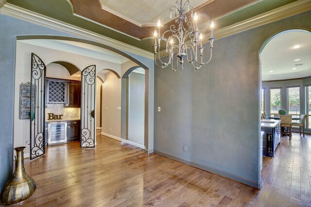 18931 Winding Atwood Ln, Tomball, TX 77377 - dining area with wine cooler, arched walkways, a dry bar, ornamental molding, and wood finished floors