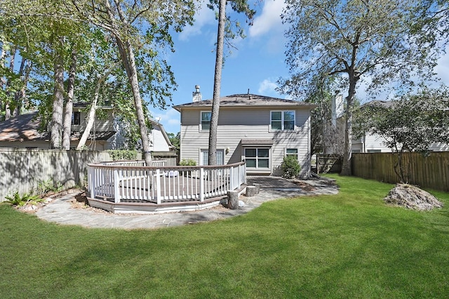 back of house featuring a fenced backyard, a chimney, a wooden deck, and a yard