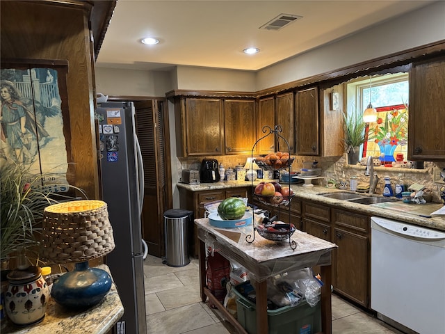 kitchen featuring freestanding refrigerator, visible vents, dishwasher, light countertops, and a sink