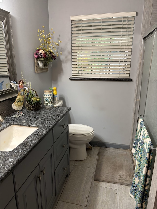 full bathroom featuring vanity, baseboards, an enclosed shower, toilet, and wood tiled floor