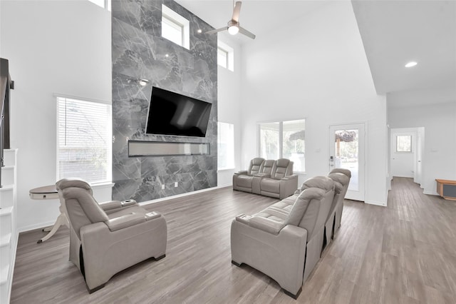 living room with a high ceiling, a premium fireplace, baseboards, and wood finished floors