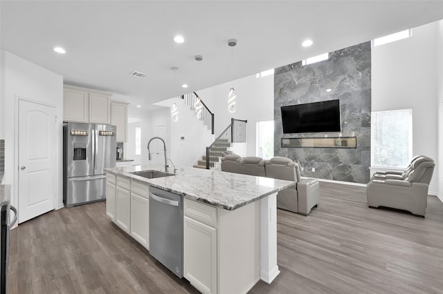 kitchen featuring open floor plan, appliances with stainless steel finishes, wood finished floors, and a sink